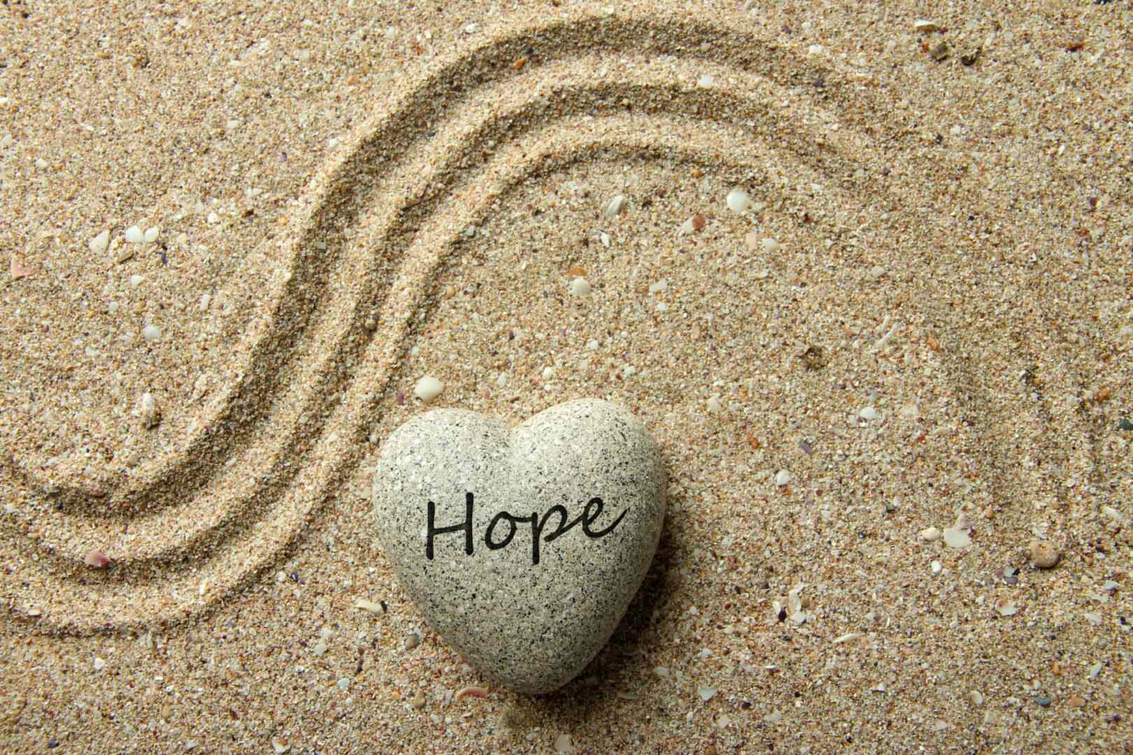 A heart-shaped stone marked &ldquo;Hope&rdquo; resting in raked sand